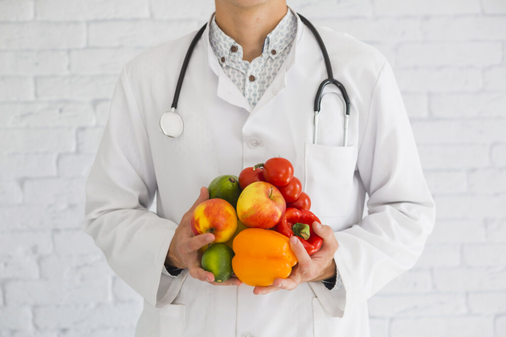 medico con della frutta e della verdura in mano